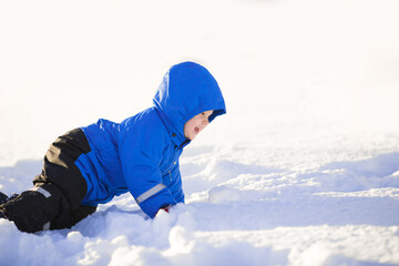 Fototapeta na wymiar Kid walks in the winter like a little snowman. Cute baby Toddler playing in the snow. Children have fun outside in winter.