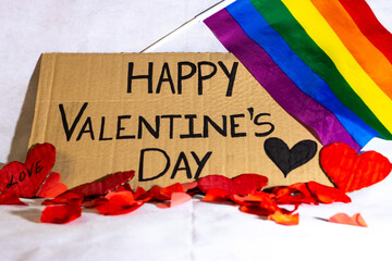 close-up of a sign on which is written happy Valentine's Day with hearts LGBT flag on white background. Valentine's Day celebration for homosexual couple