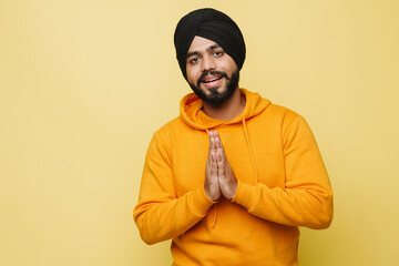 Bearded south asian man making prayer gesture while smiling