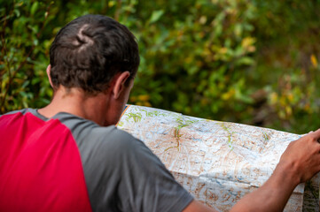 Caucasian man looking at trekking path on map. Navigating. Karakol valley, Issyk-kul region, Ala-kul lake Terskey Alatau mountain range, Kyrgyzstan, Central Asia.