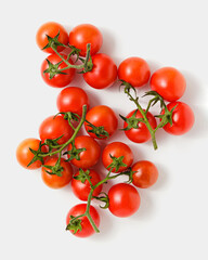 Cherry tomatoes on branches on white background.
