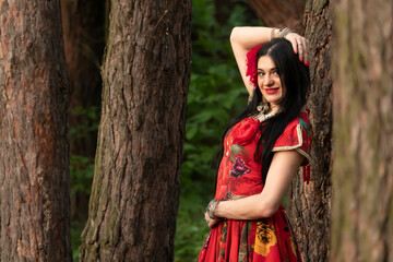 Gypsy woman. Red long dress. Portrait of a girl in an ethnic costume in the forest. The gypsy brunette is beautiful.