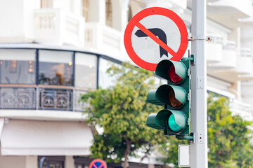 A road sign turning left is prohibited and a traffic light regulating traffic