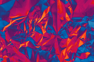 Photo texture of glossy metal surface in holographic spectral palette. Shiny foil in orange,...