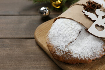 Decorated traditional Christmas Stollen with festive decor on wooden table, closeup. Space for text