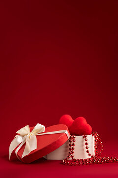 a box with gifts for the happy Valentine's day in the form of hearts. red background vertical photo copyspace mockup