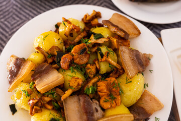 traditional rustic dish. fried potatoes with chanterelle mushrooms and pork brisket with herbs