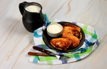 sirniki or traditional russian pancakes from cottage cheese. Served n clay plate, with sour cream and milk