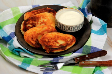 sirniki or traditional russian pancakes from cottage cheese. Served n clay plate, with sour cream and milk