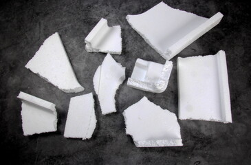 Styrofoam Sheets of different shapes on black background. Pieces of white styrofoam close up. Crumbled styrofoam pieces isolated on dark background