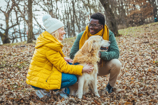 Young happy couple walking with dog near the lake in autumn. Couple Walking Dog Through Winter Woodland With Linked Arms. Couple with pet dog relaxing while hiking at forest