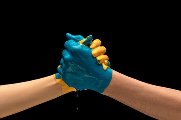 Two painted human hands handshaking isolated on dark studio background. Concept of human relation,...