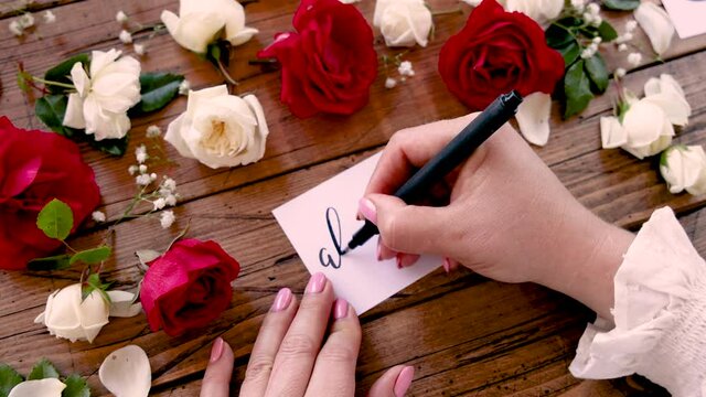 Writing ALWAYS on a card near flowers close up