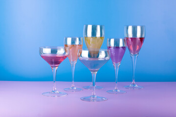 Various cocktail glasses with colorful drink on blue and pink background. Cocktail party concept