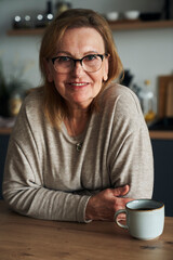 Portrait of caucasian senior woman leaning in the kitchen island