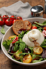 Delicious burrata salad with colorful cherry tomatoes, croutons and arugula on wooden table, closeup