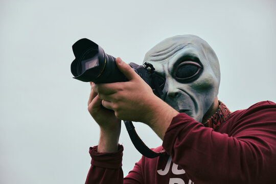 Persona disfrazada con una máscara de alienígena sacando fotos con una cámara