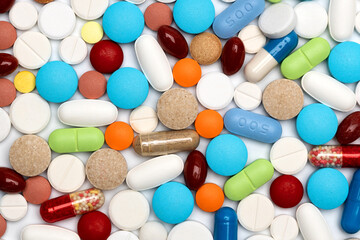 Assorted colored pills and capsules on white. Background from colored tablets and capsules...