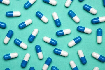 Pills pattern. Set of blue tablets on green background. Pattern made with pharmaceutical medicine capsules. Medicine concept.