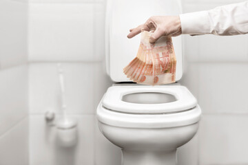 a man's hand throws Russian Russian money rubles bills into the toilet. financial crisis in Russia...
