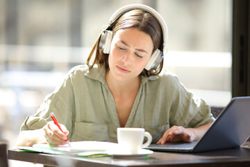 Woman e-learning with laptop and headphones taking notes