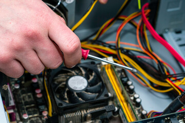 a master with a screwdriver in his hand repairs an old dusty computer