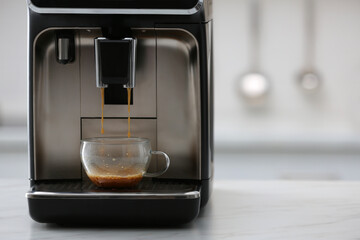 Modern electric espresso machine making coffee on white marble countertop in kitchen