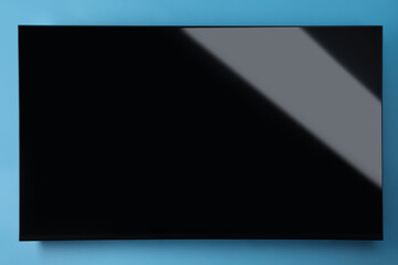 Modern TV with blank wide screen on light blue background
