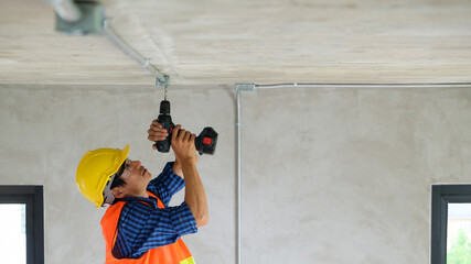 Worker craftsman technician are repair drilling or fixing ceiling the wire socket with electrical...