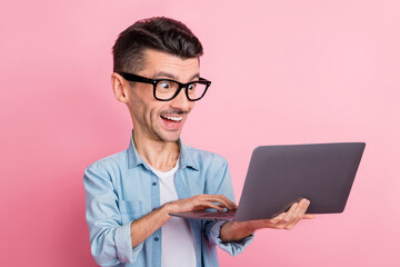 Portrait of nice cheerful large funny face guy holding in hands using laptop isolated over pink...