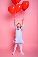 Beautiful child girl with red heart romantic balloons on pink background. Concept of Valentines day