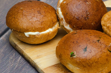 Garlic buns cut in half and smeared with melted cheese with ham on a wooden board