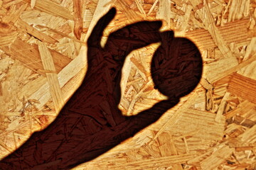 OSB board. Wood structure. Shadow. A game of shadows and lights. Hand with balloon. Detail view. Working desk. Wooden wall. Glued wood. Wooden background.