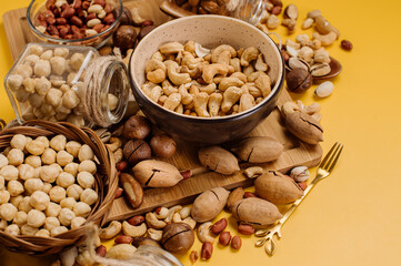 Mix of different types of dried nuts in compositions on a yellow background. Top view. Flat lay