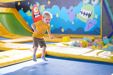 cute blond little boy jumps in a trampoline park, children activity