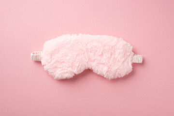 Top view photo of pink fluffy sleeping mask on isolated pastel pink background with copyspace