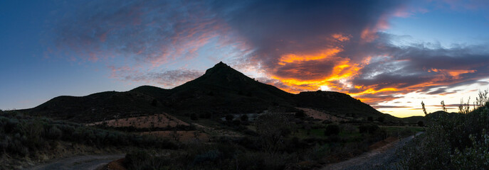 panorama of a Spanish desert and mountain landscape with a colorful and expressive sunset sky