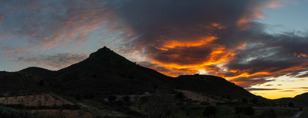 panorama of a Spanish desert and mountain landscape with a colorful and expressive sunset sky