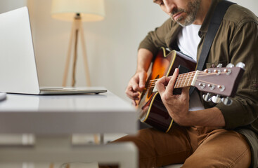 Musical performance online. Man plays acoustic guitar at home in front of online audience or...