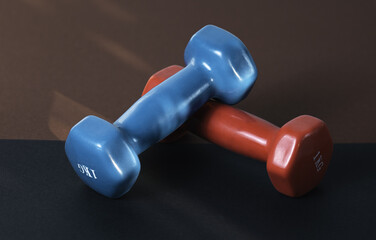 Two small blue and red dumbbells on dark background