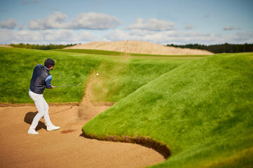 Golfer hits out of a sand trap, bunker