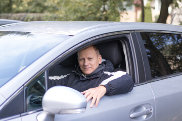 middle-aged man, 55-60 years old, driver, sits in a car and smiles
