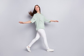 Fototapeta na wymiar Full body profile photo of funny brunette lady go look empty space wear blouse trousers footwear isolated on grey color background