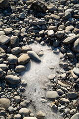 Patch of frozen water between white stones