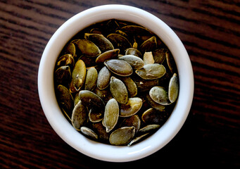 small bowl with pumpkin seeds close up on the black table