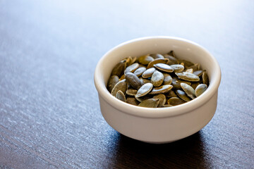 small bowl with pumpkin seeds close up on the black table