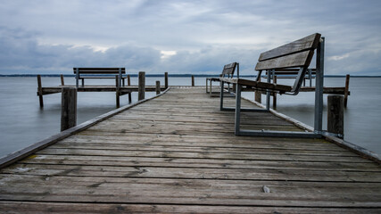 Fototapeta na wymiar Wooden jetty with benches by the sea