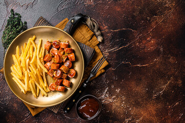 German currywurst sausage, curry wurst served with French fries. Dark background. Top view. Copy...