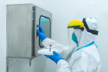 A Medical technician about to open a pass box to place a test sample at a cleanroom at a laboratory.