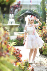 Beautiful young woman with white lolita dress with flowers garden Japanese fashion